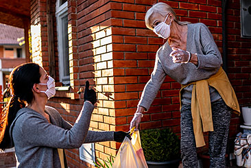 volunteer passing groceries to a mature woman